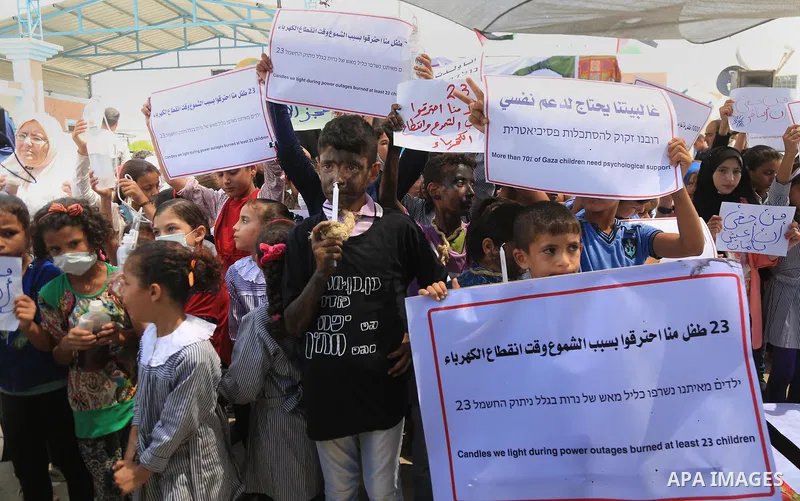 Palestinian children hold banners and candles during in a protest against the continued Israeli siege on the Gaza Strip, at Erez crossing, in the northern Gaza Strip on July 24, 2018. Photo by Dawoud Abo Alkas