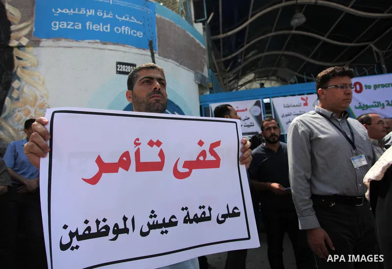 Palestinian employees of United Nations Relief and Works Agency (UNRWA) hold a sign during a protest against a U.S. decision to cut aid, in front of the headquarters UNRWA, in Gaza City on July 24, 2018. Photo by Mahmoud...