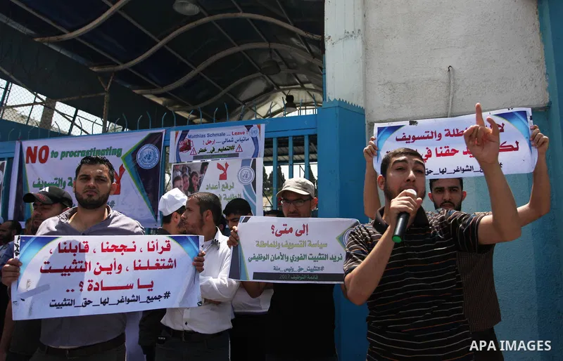 Palestinian employees of United Nations Relief and Works Agency (UNRWA) hold a sign during a protest against a U.S. decision to cut aid, in front of the headquarters UNRWA, in Gaza City on July 24, 2018. Photo by Mahmoud...