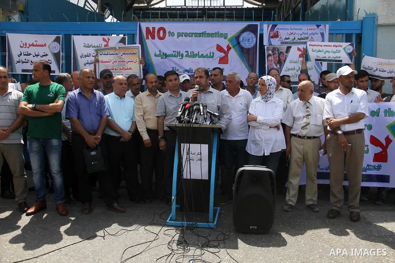 Palestinian employees of United Nations Relief and Works Agency (UNRWA) hold a sign during a protest against a U.S. decision to cut aid, in front of the headquarters UNRWA, in Gaza City on July 24, 2018. Photo by Mahmoud...