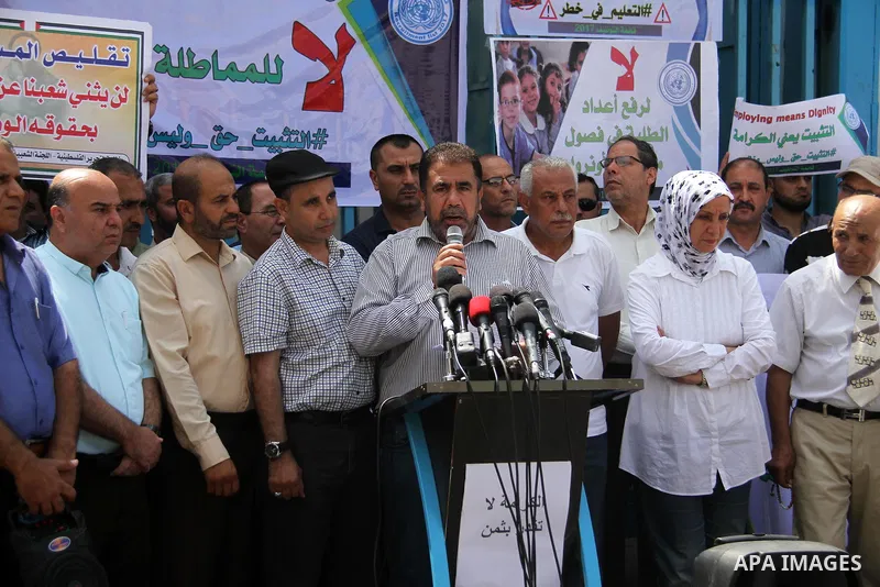 Palestinian employees of United Nations Relief and Works Agency (UNRWA) hold a sign during a protest against a U.S. decision to cut aid, in front of the headquarters UNRWA, in Gaza City on July 24, 2018. Photo by Mahmoud...