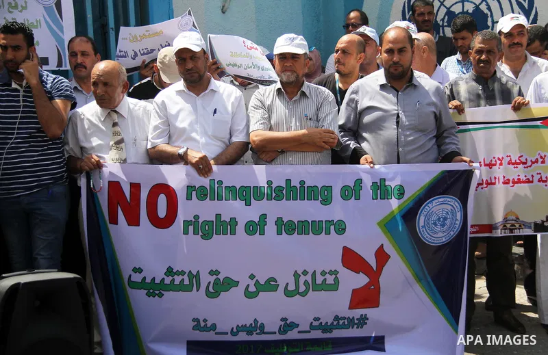 Palestinian employees of United Nations Relief and Works Agency (UNRWA) hold a sign during a protest against a U.S. decision to cut aid, in front of the headquarters UNRWA, in Gaza City on July 24, 2018. Photo by Mahmoud...
