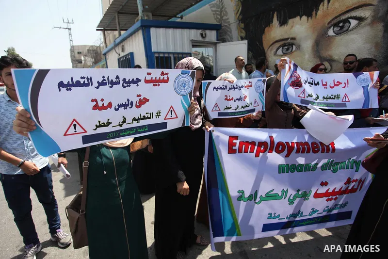 Palestinian employees of United Nations Relief and Works Agency (UNRWA) hold a sign during a protest against a U.S. decision to cut aid, in front of the headquarters UNRWA, in Gaza City on July 24, 2018. Photo by Mahmoud...