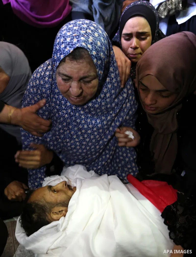 Relatives of Palestinian Majdi Oqeel, who died of wounds he sustained during clashes with Israeli troops, mourn over his body during his funeral, in Jabalia in the northern of Gaza Strip on July 24, 2018. Photo by Ashraf...
