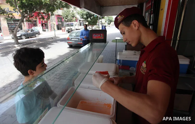 A Palestinian vendor sells ice-cream (sundae) to customers during a heatwave in Gaza city on July 25, 2018. Photo by Mahmoud Ajour