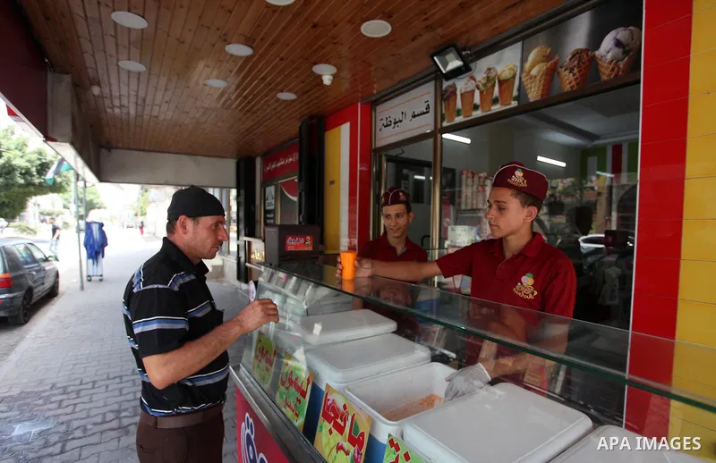 Palestinian vendors sell ice-cream (sundae) to customers during a heatwave in Gaza city on July 25, 2018. Photo by Mahmoud Ajour
