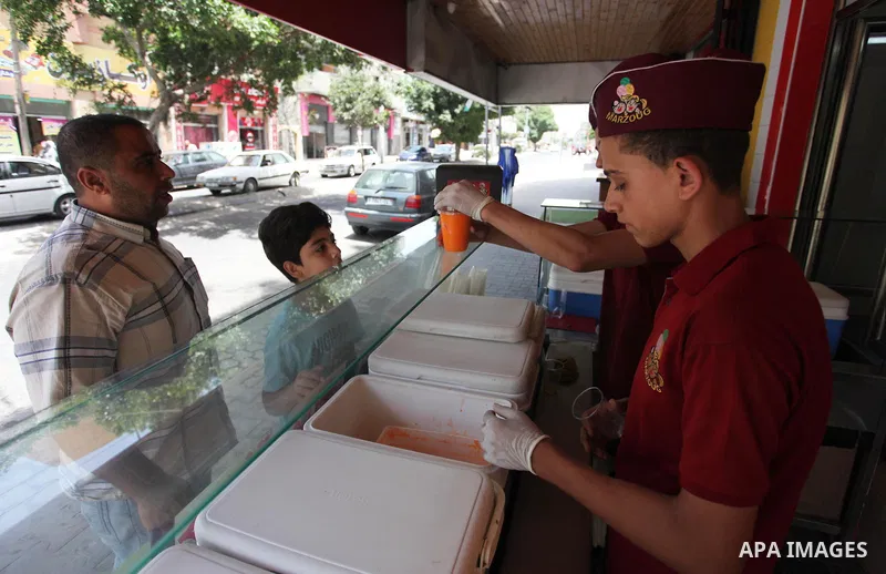 A Palestinian vendor sells ice-cream (sundae) to customers during a heatwave in Gaza city on July 25, 2018. Photo by Mahmoud Ajour