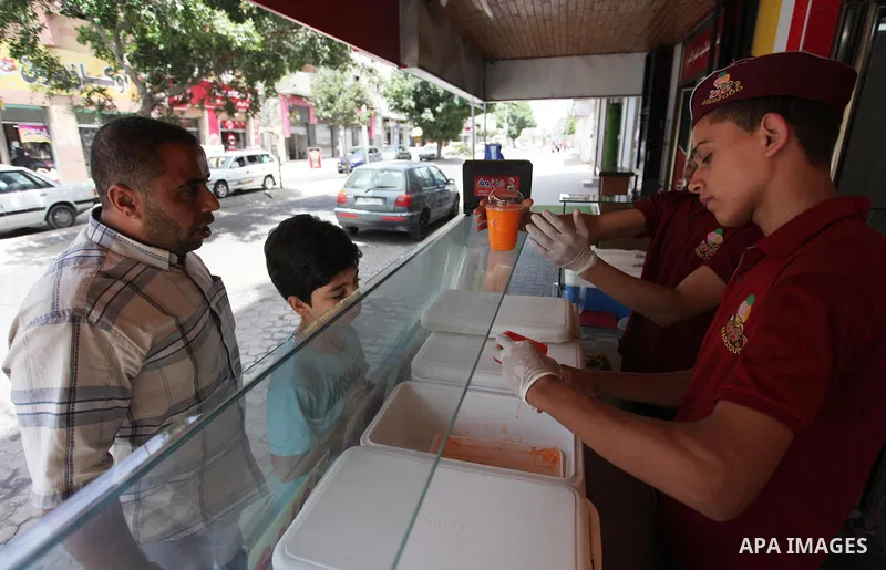 Palestinian vendors sell ice-cream (sundae) to customers during a heatwave in Gaza city on July 25, 2018. Photo by Mahmoud Ajour