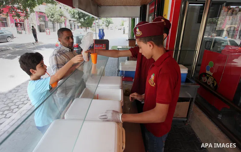 Palestinian vendors sell ice-cream (sundae) to customers during a heatwave in Gaza city on July 25, 2018. Photo by Mahmoud Ajour