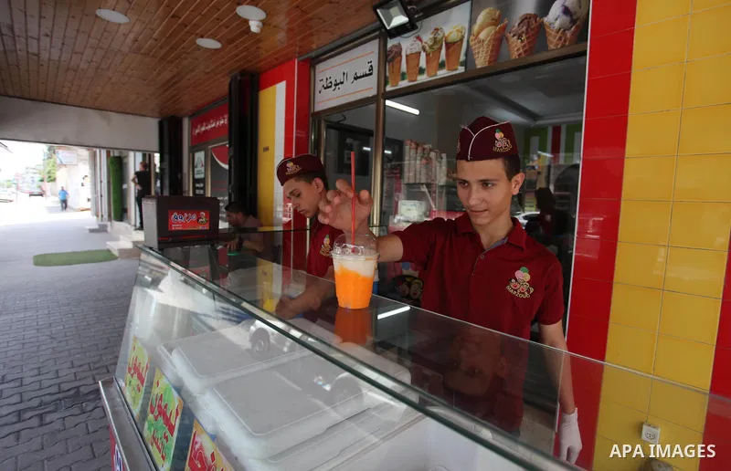 Palestinian vendors sell ice-cream (sundae) to customers during a heatwave in Gaza city on July 25, 2018. Photo by Mahmoud Ajour