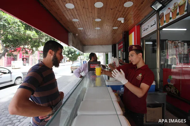 A Palestinian vendor sells ice-cream (sundae) to customers during a heatwave in Gaza city on July 25, 2018. Photo by Mahmoud Ajour
