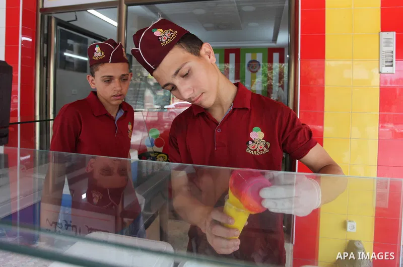 Palestinian vendors sell ice-cream (sundae) to customers during a heatwave in Gaza city on July 25, 2018. Photo by Mahmoud Ajour