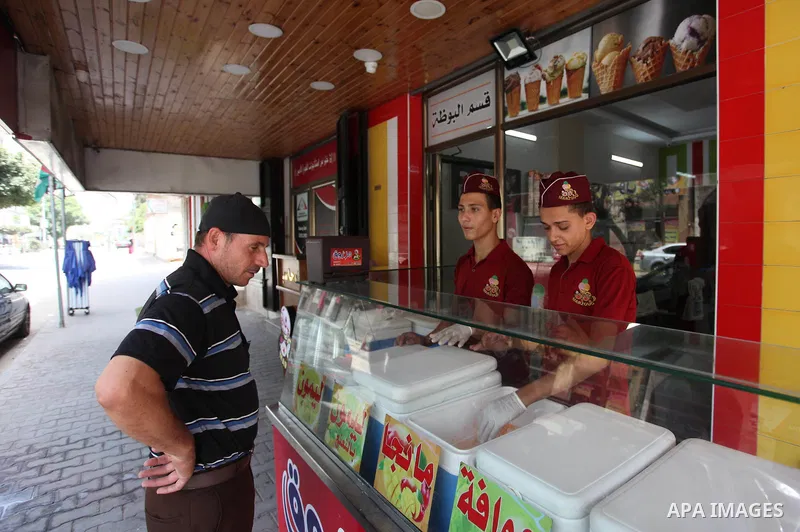 Palestinian vendors sell ice-cream (sundae) to customers during a heatwave in Gaza city on July 25, 2018. Photo by Mahmoud Ajour