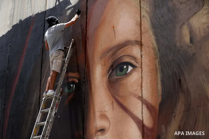 Italian artist Jorit Agoch paints a mural depicting Palestinian teenager Ahed Tamimi on Israel's controversial separation barrier in the West Bank city of Bethlehem, on July 25,2018. Tamimi, was charged earlier this year...