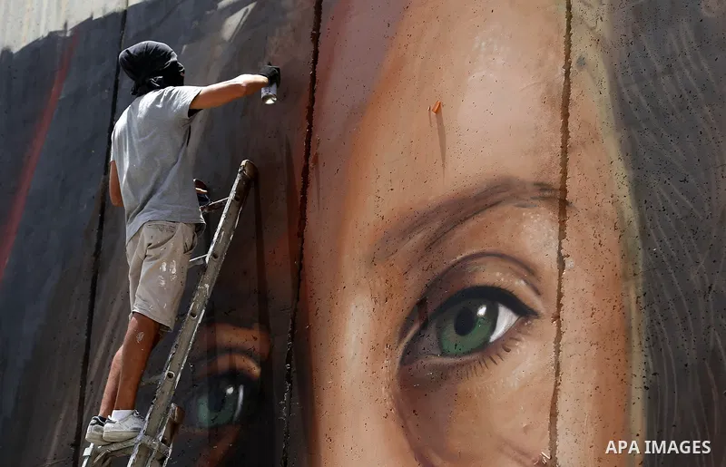 Italian artist Jorit Agoch paints a mural depicting Palestinian teenager Ahed Tamimi on Israel's controversial separation barrier in the West Bank city of Bethlehem, on July 25,2018. Tamimi, was charged earlier this year...
