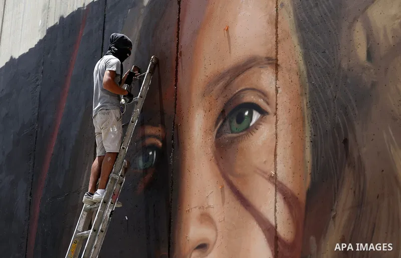 Italian artist Jorit Agoch paints a mural depicting Palestinian teenager Ahed Tamimi on Israel's controversial separation barrier in the West Bank city of Bethlehem, on July 25,2018. Tamimi, was charged earlier this year...