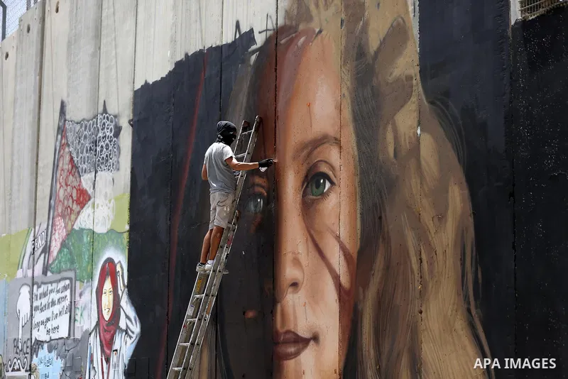 Italian artist Jorit Agoch paints a mural depicting Palestinian teenager Ahed Tamimi on Israel's controversial separation barrier in the West Bank city of Bethlehem, on July 25,2018. Tamimi, was charged earlier this year...