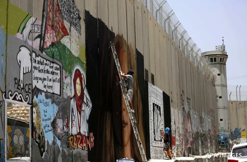 Italian artist Jorit Agoch paints a mural depicting Palestinian teenager Ahed Tamimi on Israel's controversial separation barrier in the West Bank city of Bethlehem, on July 25,2018. Tamimi, was charged earlier this year...