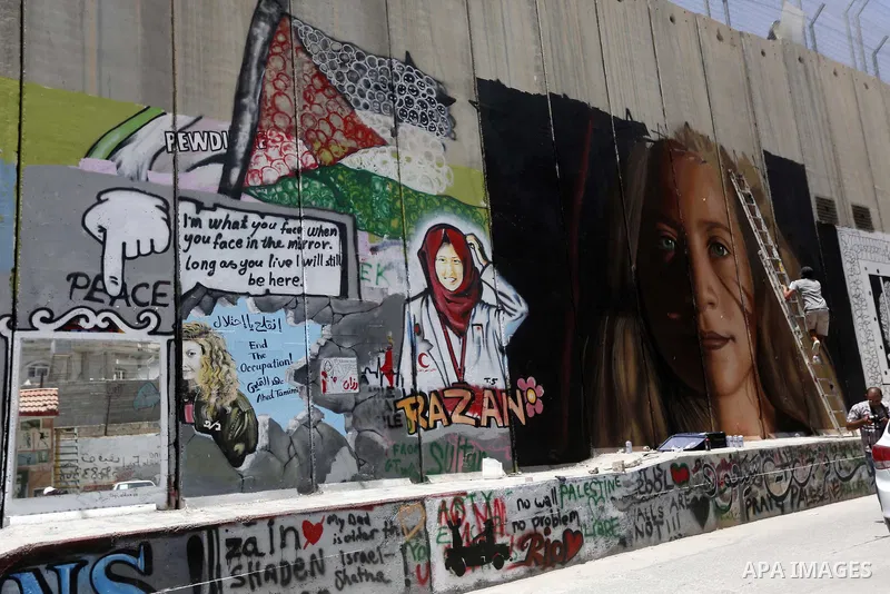 Italian artist Jorit Agoch paints a mural depicting Palestinian teenager Ahed Tamimi on Israel's controversial separation barrier in the West Bank city of Bethlehem, on July 25,2018. Tamimi, was charged earlier this year...