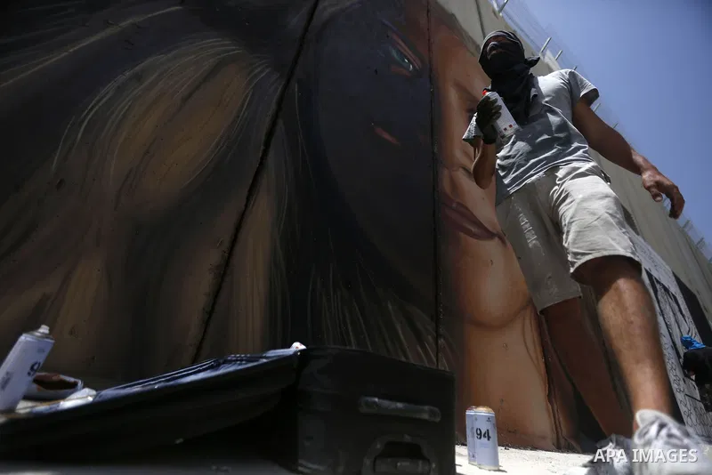 Italian artist Jorit Agoch paints a mural depicting Palestinian teenager Ahed Tamimi on Israel's controversial separation barrier in the West Bank city of Bethlehem, on July 25,2018. Tamimi, was charged earlier this year...