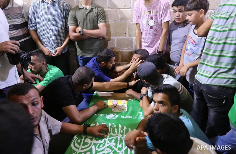 Mourners gather around the body of Palestinian Hamas militant Ahmed Albassous who was killed in Israeli tank fire, during his funeral at Omari Mosque in Gaza City July 26, 2018. Photo by Ashraf Amra