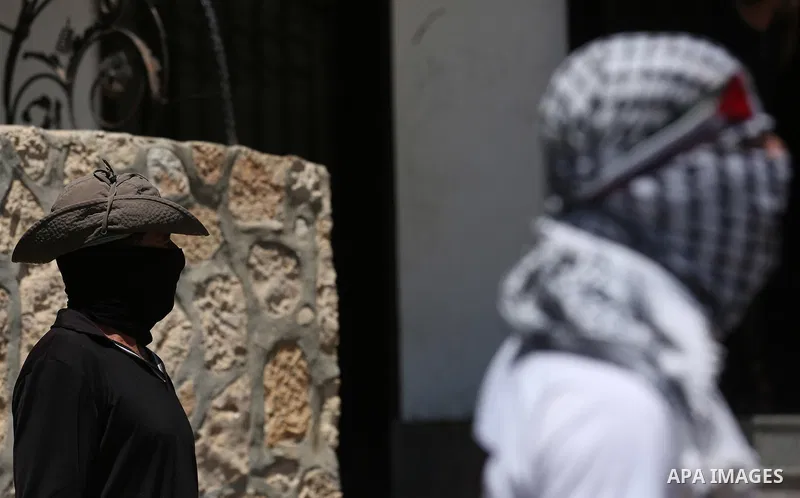 Masked Palestinian protesters look on during clashes with Israeli troops following a demonstration against the expropriation of Palestinian land by Israel in the village of Kfar Qaddum, near Nablus, in the occupied West...