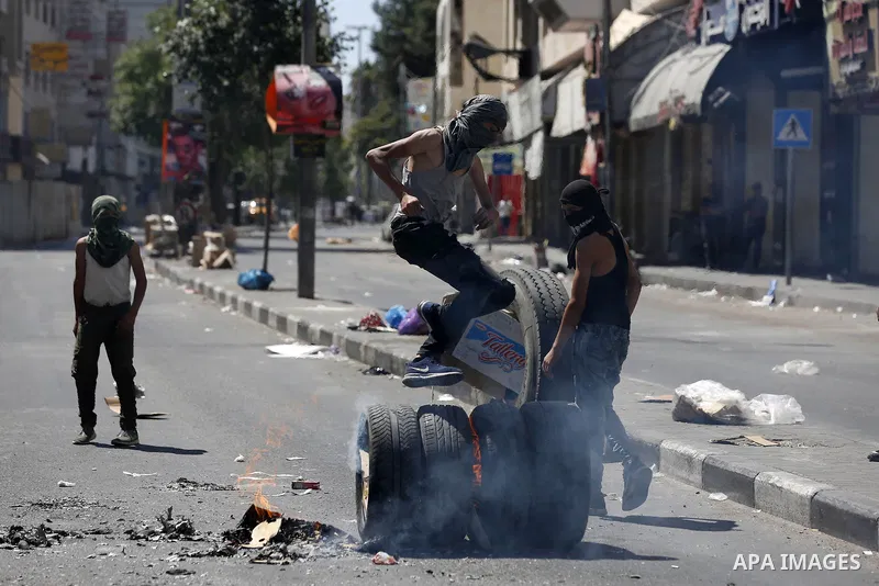 Palestinian protesters burn tyres during clashes following a demonstration, in the West Bank city of Hebron, on July 27, 2018. Photo by Wisam Hashlamoun