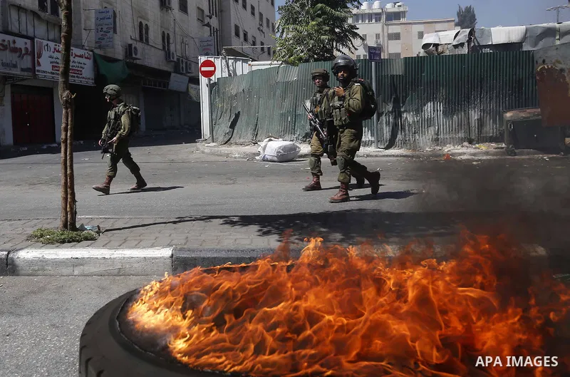 Palestinian protesters burn tyres during clashes following a demonstration, in the West Bank city of Hebron, on July 27, 2018. Photo by Wisam Hashlamoun