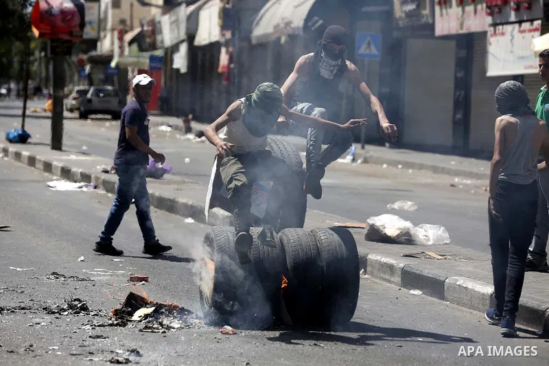 Palestinian protesters burn tyres during clashes following a demonstration, in the West Bank city of Hebron, on July 27, 2018. Photo by Wisam Hashlamoun