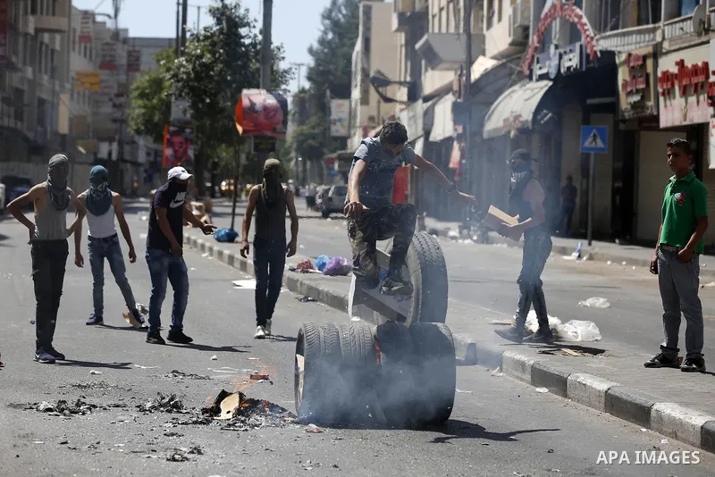 Palestinian protesters burn tyres during clashes following a demonstration, in the West Bank city of Hebron, on July 27, 2018. Photo by Wisam Hashlamoun