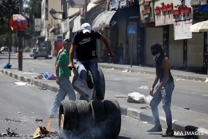 Palestinian protesters burn tyres during clashes following a demonstration, in the West Bank city of Hebron, on July 27, 2018. Photo by Wisam Hashlamoun