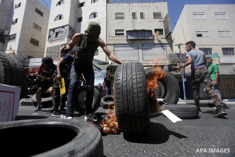 Palestinian protesters burn tyres during clashes following a demonstration, in the West Bank city of Hebron, on July 27, 2018. Photo by Wisam Hashlamoun
