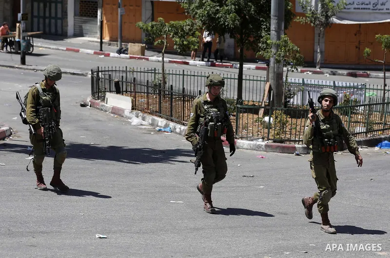 Israeli troops take position during clashes with Palestinian protesters in the West Bank city of Hebron on July 27, 2018. Photo by Wisam Hashlamoun
