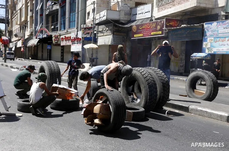 Palestinian protesters burn tyres during clashes following a demonstration, in the West Bank city of Hebron, on July 27, 2018. Photo by Wisam Hashlamoun