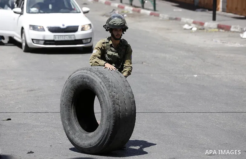 An Israeli troop kicks a tyre during clashes with Palestinian protesters in the West Bank city of Hebron on July 27, 2018. Photo by Wisam Hashlamoun