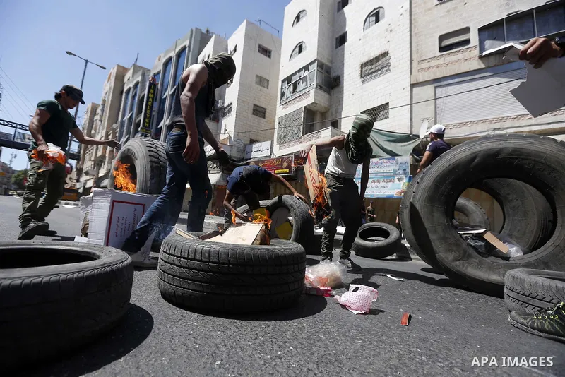 Palestinian protesters burn tyres during clashes following a demonstration, in the West Bank city of Hebron, on July 27, 2018. Photo by Wisam Hashlamoun