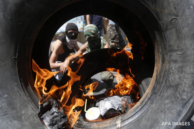 Palestinian protesters burn tyres during clashes following a demonstration, in the West Bank city of Hebron, on July 27, 2018. Photo by Wisam Hashlamoun