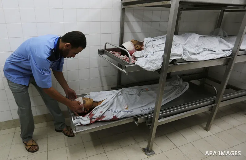 A medic stands over the bodies of 11-year-old Majdi Al-Sutari and 43-year-old Ghazi Abu Mustafa, who were killed during a demonstration along the border between Israel and the Gaza strip, at the morgue of the European Ho...
