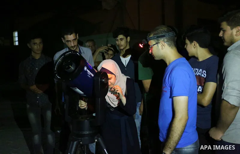 Palestinians inspect the total lunar eclipse by a telescope in the sky of Khan Younis in the southern of Gaza Strip on July 27, 2018. The longest "blood moon" eclipse this century began on July 27, coinciding with Mars'...