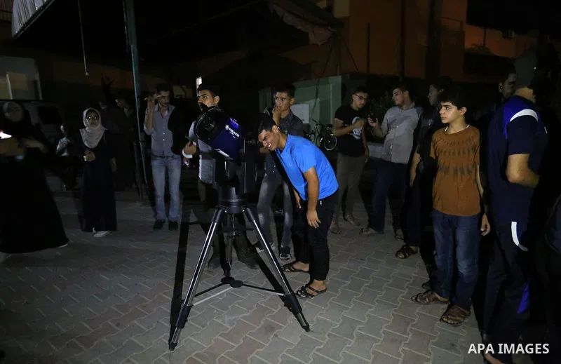 Palestinians inspect the total lunar eclipse by a telescope in the sky of Khan Younis in the southern of Gaza Strip on July 27, 2018. The longest "blood moon" eclipse this century began on July 27, coinciding with Mars'...