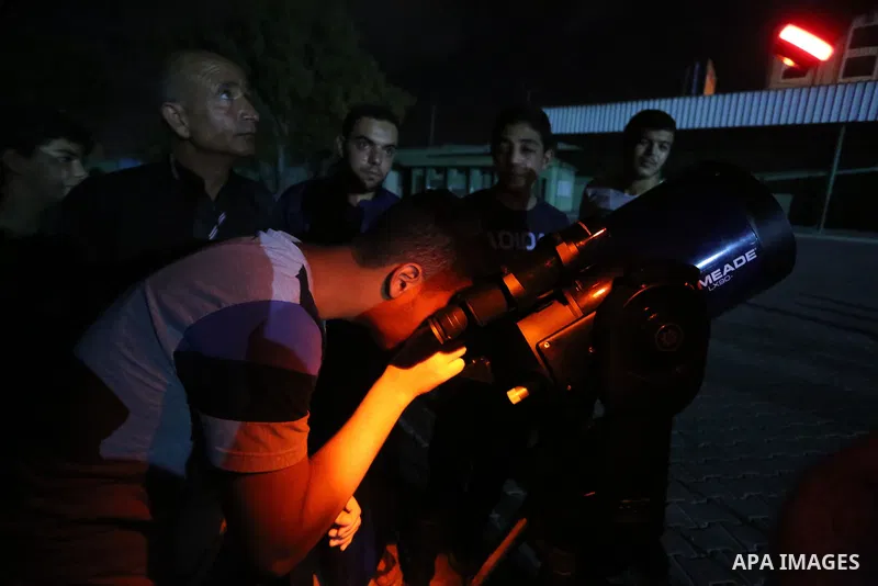 Palestinians inspect the total lunar eclipse by a telescope in the sky of Khan Younis in the southern of Gaza Strip on July 27, 2018. The longest "blood moon" eclipse this century began on July 27, coinciding with Mars'...
