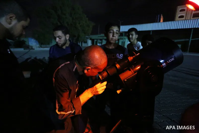 Palestinians inspect the total lunar eclipse by a telescope in the sky of Khan Younis in the southern of Gaza Strip on July 27, 2018. The longest "blood moon" eclipse this century began on July 27, coinciding with Mars'...