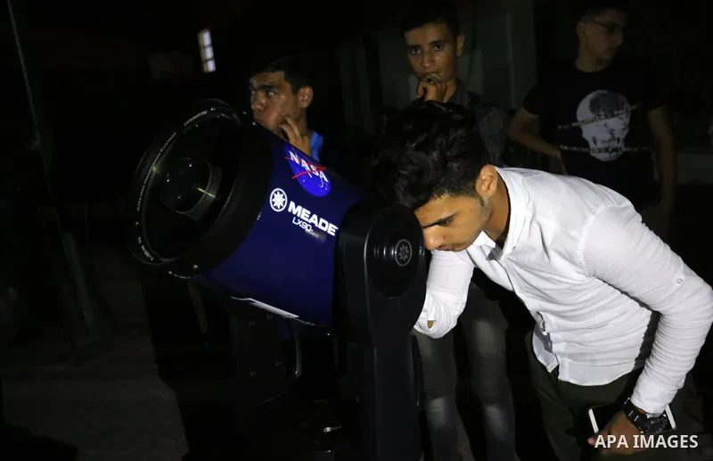 Palestinians inspect the total lunar eclipse by a telescope in the sky of Khan Younis in the southern of Gaza Strip on July 27, 2018. The longest "blood moon" eclipse this century began on July 27, coinciding with Mars'...