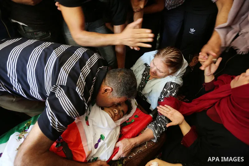 Relatives of Palestinian Mohmen al-Hams, 17, who died of wounds after being shot by Israeli troops during clashes along the border the previous day mourn over his body during his funeral in the Rafah refugee camp in the...