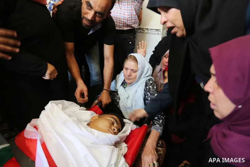 Relatives of Palestinian Mohmen al-Hams, 17, who died of wounds after being shot by Israeli troops during clashes along the border the previous day mourn over his body during his funeral in the Rafah refugee camp in the...
