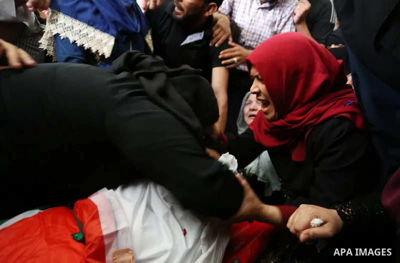 Relatives of Palestinian Mohmen al-Hams, 17, who died of wounds after being shot by Israeli troops during clashes along the border the previous day mourn over his body during his funeral in the Rafah refugee camp in the...