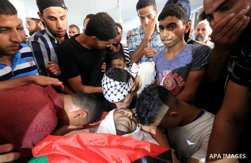 Relatives of Palestinian Ghazi Abu Mustafa, 43, who was shot dead by Israeli troops during clashes along the border the previous day, mourn over his body during his funeral in Khan Younis in the southern Gaza Strip on Ju...