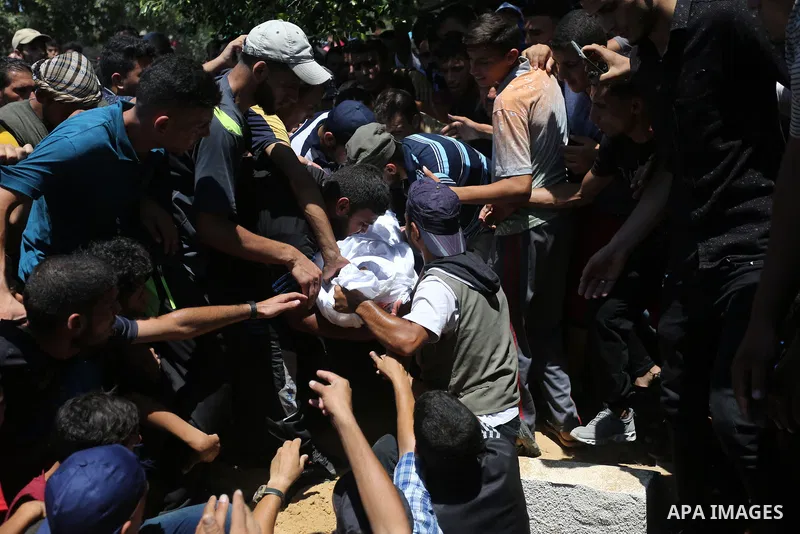 Mourners bury the body of Majdi al-Sutari, 11, who was shot dead by Israeli troops during clashes along the border the previous day, during his funeral in Rafah in the southern Gaza Strip on July 28, 2018. Photo by Ashra...