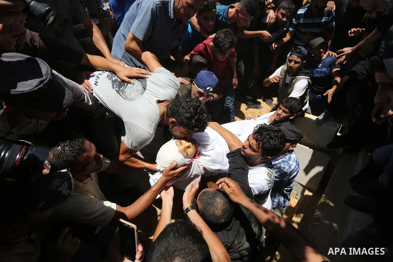 Mourners bury the body of Majdi al-Sutari, 11, who was shot dead by Israeli troops during clashes along the border the previous day, during his funeral in Rafah in the southern Gaza Strip on July 28, 2018. Photo by Ashra...