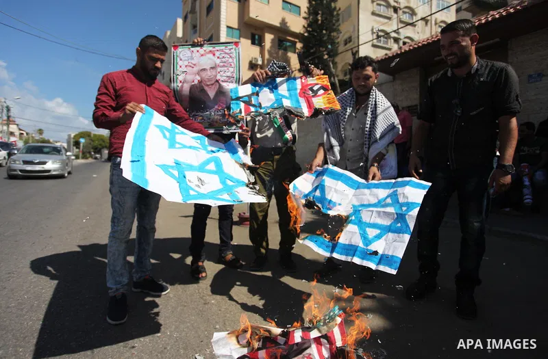 Palestinians burn an Israeli, British and U.S. flags during a protest to show solidarity with Palestinian prisoners held in Israeli jails, in front of Red cross office in Gaza city on July 30, 2018. Photo by Mahmoud Ajou...